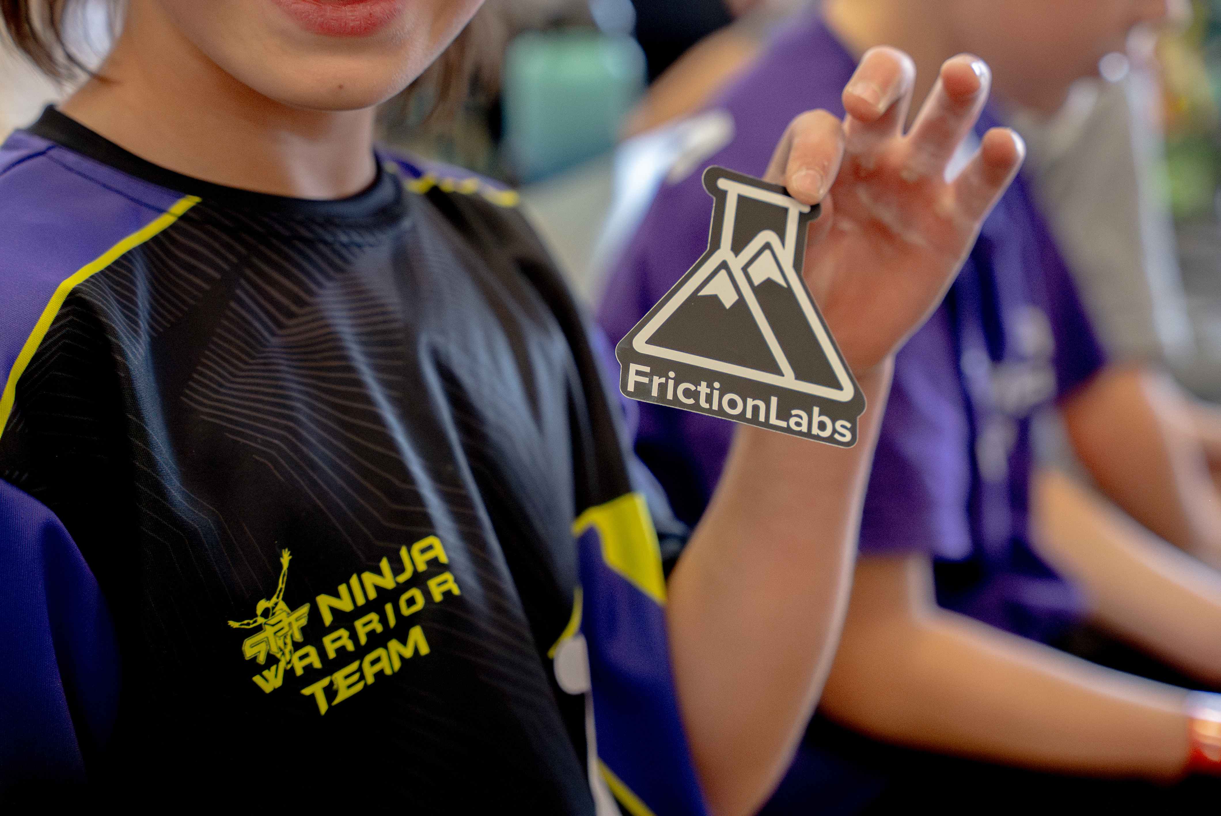 NES athlete proudly holding a FrictionLabs sticker at competition